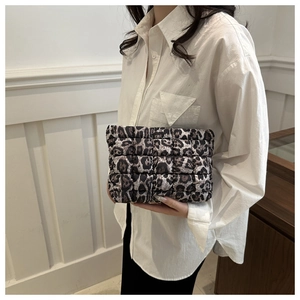Detail of leopard print quilted clutch bag held by model showing texture and size