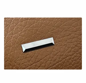 Macro detail of brown lychee grain leather texture and a rectangular silver metal piece