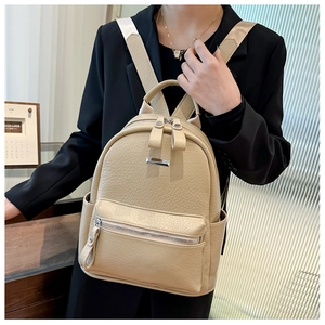 Close-up of beige soft PU leather backpack showing lychee texture and silver metal plate