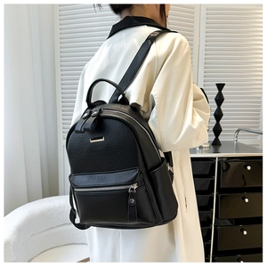 Detail of black pebbled PU leather backpack with silver zippers and metal logo plate