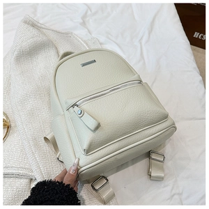 Close-up of beige faux leather backpack showing litchi texture and metal logo plaque