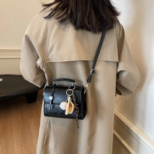 Vintage black leather satchel with baseball charm on model in minimalist interior