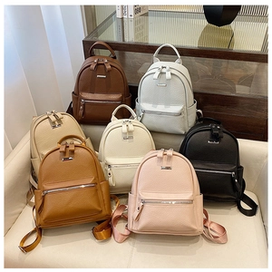 Detailed pile of mini backpacks in various colors with textured vegan leather and silver zippers