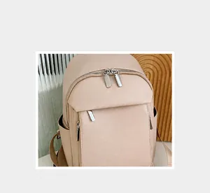 Detailed close-up of beige lychee grain leather backpack with metallic zippers