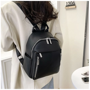 Rear view of model wearing a black PU leather backpack with silver zippers and soft texture