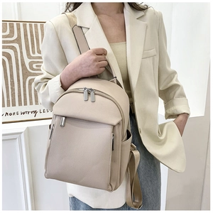 Macro detail of beige pebble grain leather texture and metallic zippers on the backpack