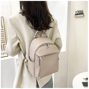 Detail of beige faux leather backpack with litchi texture and front zipper pocket