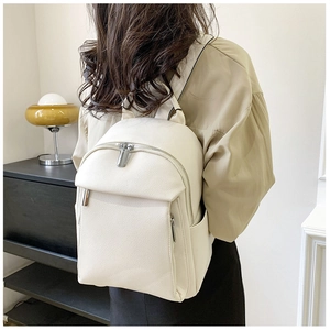 Rear view of a model wearing the cream white soft PU leather backpack in a home setting