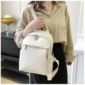 Detailed view of the off-white lychee grain leather texture and silver zippers of the backpack