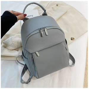Detailed view of gray faux leather backpack featuring textured lychee grain and silver zippers