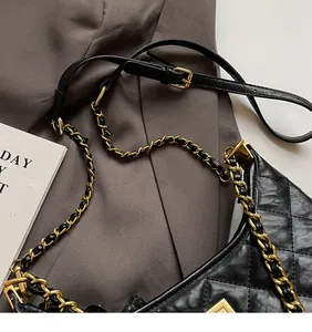 Detail of black quilted leather tote with gold metal chain and adjustable strap