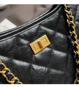 Close-up of golden rectangular twist lock on black quilted leather chain tote bag