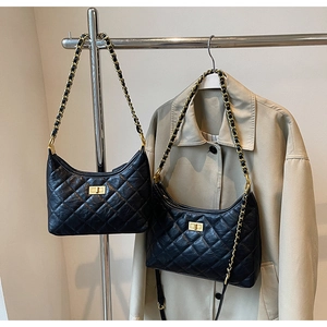 Detail of black quilted chain bags with gold hardware hanging next to a trench coat