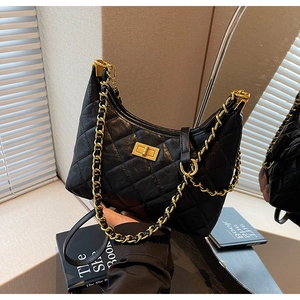 Detail of black quilted leather shoulder bag featuring a gold chain strap and turn-lock