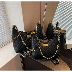 Detail of black quilted leather tote with gold metal chain straps and square turn-lock