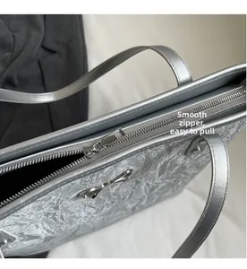 Détail de la fermeture éclair argentée fluide sur un sac seau plissé métallisé
