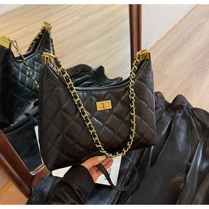 Detailed close-up of a quilted black leather tote bag with a golden turn-lock closure