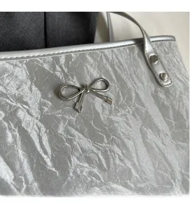 Vue détaillée du sac seau argenté avec texture plissée et décoration nœud en métal