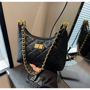 Close-up of black quilted leather texture and chunky gold chain strap on the tote bag