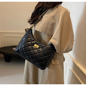 Close-up of black quilted leather shoulder bag with gold clasp and chain strap
