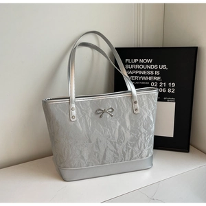 Détail du sac cabas argenté avec texture froissée et nœud métallique délicat