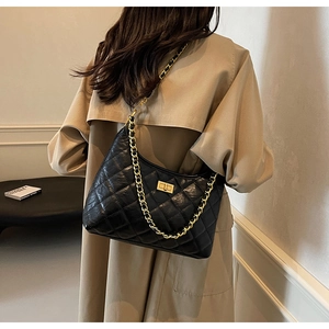 Close-up of black quilted leather bag with chunky gold chain and metallic turn-lock closure