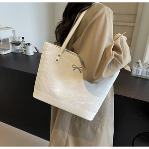 Détail du sac cabas blanc cassé à texture marbrée et nœud argenté porté par un modèle