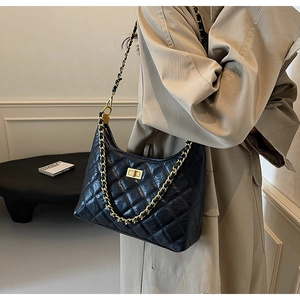 Detail of black quilted leather hobo bag with vintage gold chain strap on model
