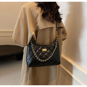 Detail of classic black quilted shoulder bag with golden chain and metallic turn-lock