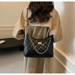 Detail of black quilted leather shoulder bag with gold chain strap and square metal lock
