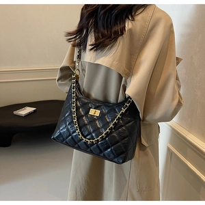 Close-up of vintage black quilted tote bag with golden metal chain and twist-lock detail