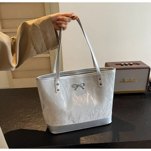 Détail d'un sac cabas argenté métallisé avec texture plissée et nœud métallique