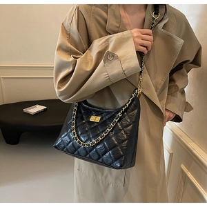 Detail of black quilted leather tote bag with gold chain strap and metal swivel lock