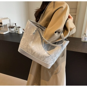 Détail du sac cabas argenté avec texture plissée artistique et bandoulière en cuir lisse