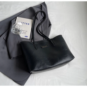 Detailed view of black textured tote bag styled with a blazer and book for daily work wear