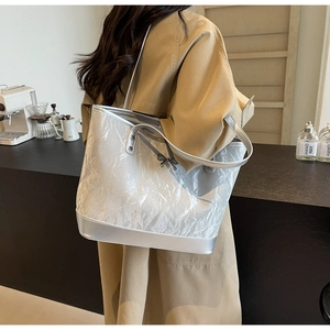 Détail du sac cabas plissé argenté avec nœud porté sur un trench-coat classique kaki