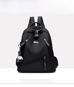 Front detail of black nylon backpack with metal zippers and cute bear charm pendant