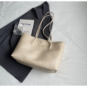 Close-up of vintage textured cream tote bag with elegant thin shoulder straps and logo