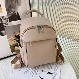 Beige minimalist pebble leather backpack with wide fabric straps and front zip pocket