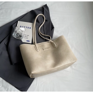 Detail of minimalist cream leather tote bag featuring natural texture and slim shoulder straps