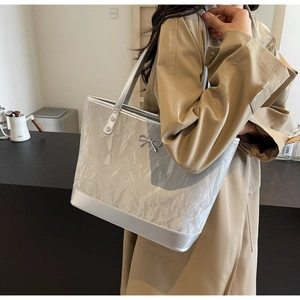 Détail du sac cabas argenté avec texture froissée et nœud métallique sur le côté