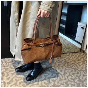 Detail of dark brown suede tote bag featuring slim leather straps and metal buckle