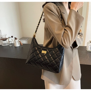Close-up of black quilted leather hobo bag with golden turn-lock and chain strap