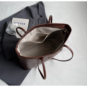 Detailed view of dark brown tote bag interior with gray lining and bronze zipper closure