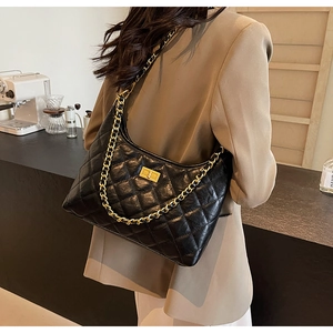 Detailed view of black quilted leather tote bag with gold chain strap on a model