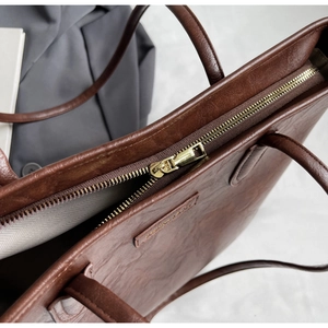 Close-up of golden zipper and textured lining on dark brown large tote bag detail