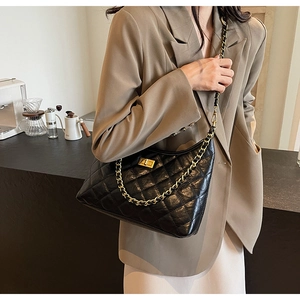 Detail of the black quilted tote bag with gold metal twist lock and chain strap