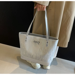 Détail du sac cabas argenté avec texture froissée métallique et décoration de nœud chic