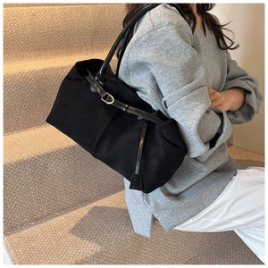 Detail of matte black tote bag showing smooth leather straps and adjustable buckle texture