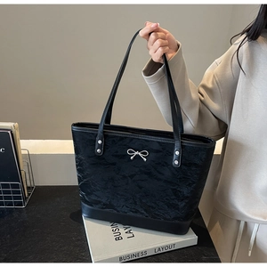 Détail du sac cabas noir avec texture froissée et ornement en forme de nœud argenté